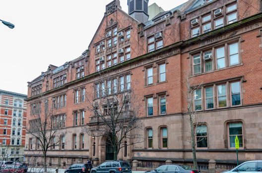 The Gottesman Libraries Building with cars parked and trees in forefront, New York City, during winter day with overcast, side view, horizontal