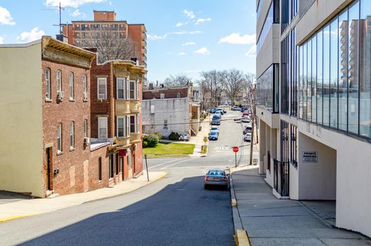 Buildings at Cliffside Park, New Jersey, downhill road, old and modern Buildings, office and residential buildings next to the street, cars parked in the background, during a sunny winter day, horizontal