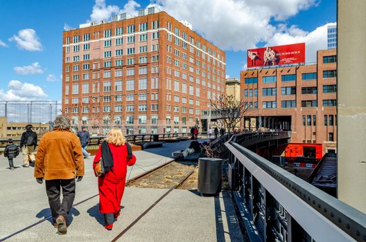 People enjoying the sun at the High Line Rooftop Park, New York City during sunny winter day, Office Buildings around the park, horizontal