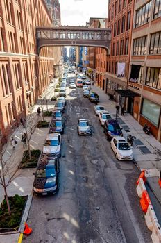 City street with lots of parked Cars in Chelsea, New York City, aerial view from the High Line Rooftop Park during sunny winter day, Bridge connecting two buildings vertical