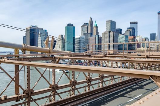 Skyline of Manhattan, New York City with brown steel construction of Brooklyn Bridge in the forefront during daytime in winter, horizontal