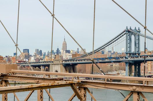 Manhattan Bridge with brown steel construction of Brooklyn Bridge in forefront, New York City, Empire State Building in the Background, horizontal