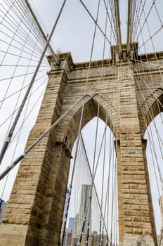 Brooklyn Bridge New York City Tower with steel wire in the forefront, view from low angle, overcast during winter day, vertical