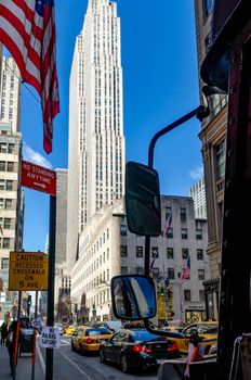 Rockefeller Center, New York City with delivery vehicle and traffic on the streets in the forefront Rockefeller center is enlightened by the sunlight during daytime and clear sky, vertical