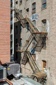 Brown colored Escape stair at a old Residential Brick wall Building in Chelsea, New York City during sunny winter day, vertical