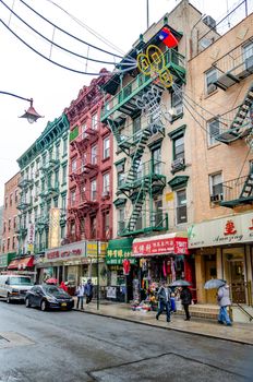 Retail Stores at China Town, New York City, People walking with umbrellas in the front of the stores, during rainy winter day with overcast, decoration above the street, vertical