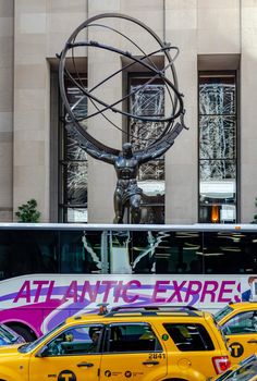 Atlas Statue at Rockefeller Center with Atlantic Express Bus and yellow taxis in front, close-up, New York City during winter day, vertical
