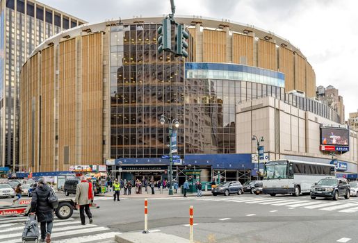 Madison Square Garden with crossroads in the front, traffic on the street and people walking around, New York City during cloudy winter day, horizontal