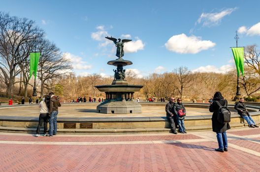 Bethesda Fountain with Angel of the Waters Sculpture, front view, Central Park New York during winter, people standing and walking around the fountain, clear sky, horizontal