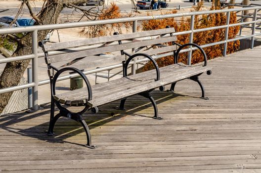 Close-up Wooden Bench at Beach Promenade of Coney island, Brooklyn, New York City during sunny winter day with cloudy sky, horizontal