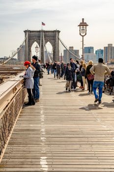 Brooklyn Bridge New York City in the evening during winter with tourists walking on the bridge, skyscraper in the background, vertical