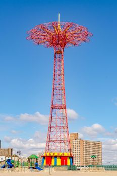 Red Parachute Jump at Luna Park Amusement Park, Coney island, Brooklyn with empty Beach in front during sunny winter day with almost clear sky, playground in front of the Tower, Low angle view, New York City, vertical