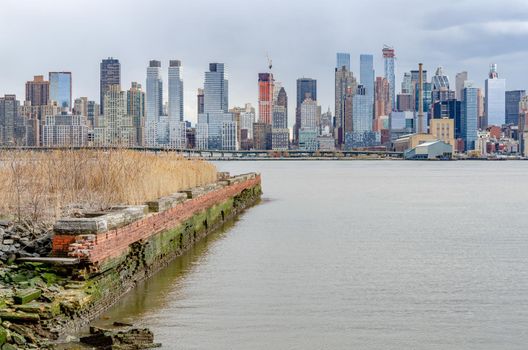 View of Manhattan Skyscraper, New York City from other side of Hudson river, New Jersey with old Building ruin om front, during cloudy winter day, horizontal