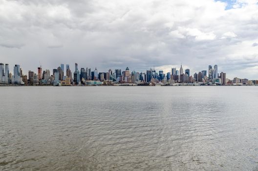 Wide angle shot of New York City Manhattan Skyline with Empire State Building and Hudson river in front during cloudy winter day, horizontal