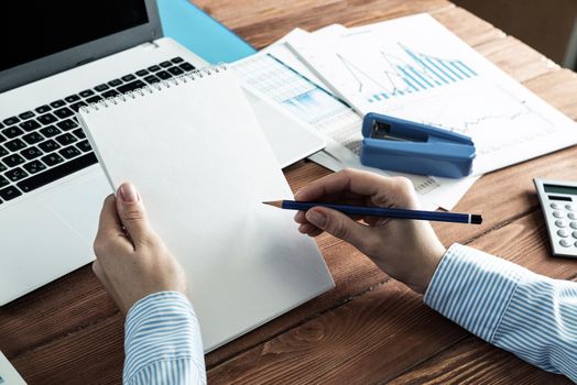 close-up, female hands hold a notebook and pencil. Business woman working at the table in the office