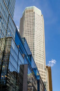 Office Building Skyscraper at Fifth Avenue view from low angle with blue glass Building facade in front, New York City during sunny winter day with clear sky, vertical