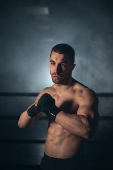 Boxer, man posing in bandage on boxing ring. Fitness and boxing concept. High quality photo