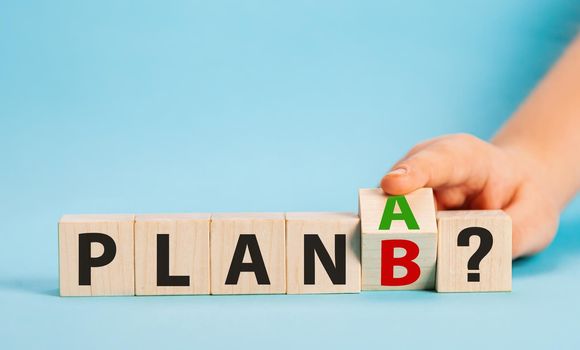 Hand flipping wooden cube blocks with PLAN A change to PLAN B text on blue background. Business plan concept, strategy, analysis, change of plan, marketing, project, and Crisis concepts.