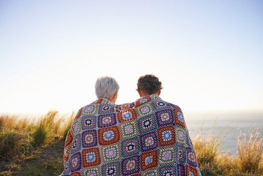 View of a senior couple sitting on a hillside together.
