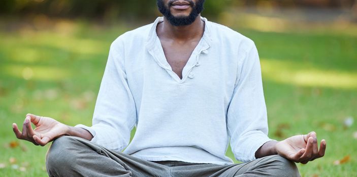 Cropped shot of an unrecognizable young man meditating while practicing yoga outside at the park.