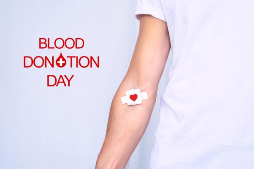 Blood donation day. Blood donor with bandage after giving blood on a white background. Copy space. High quality photo