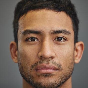 Shot of a handsome young man standing against a grey background.