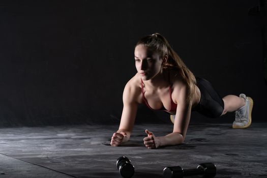 Stands on plank dumbbells girl with the in the a floor push-ups looks like a kira knightley girl fitness black, for caucasian health for exercise for training athlete, empty space sexy.