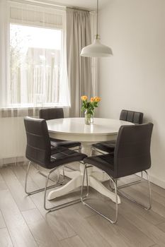 Interior of a dining area in white near to the window in a cozy house