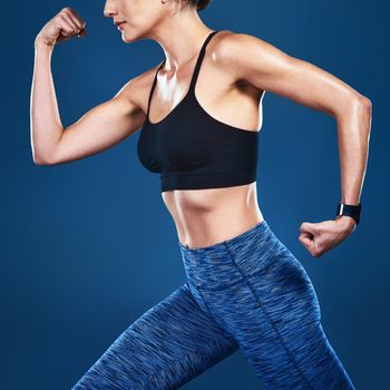 Studio shot of an unrecognizable fit woman posing against a blue background.