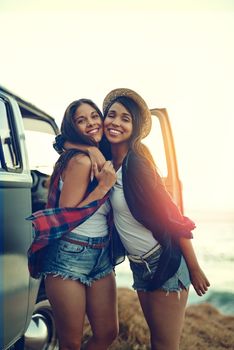 Shot of two affectionate friends stopping at the beach during their roadtrip.