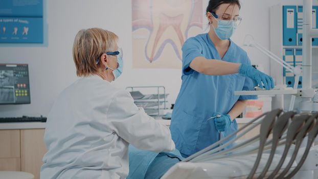 Dentist and assistant doing oral care procedure on patient with caries problems. Stomatological team using drill instrument to operate and do dental extraction, dentistry procedure.