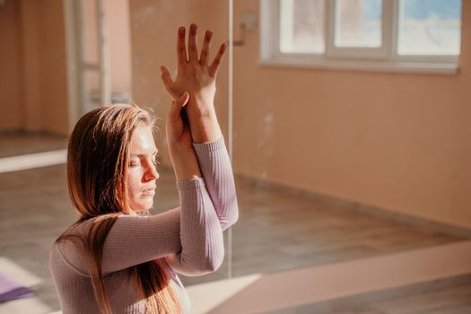 View from above. A beautiful young woman in pink sportswear is engaged in yoga, sports in the hall on a purple rug. Yoga, sport and healthy concept