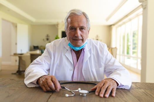 Senior caucasian male doctor wearing face mask having a video call. medicine and healthcare services during covid 19 pandemic concept.