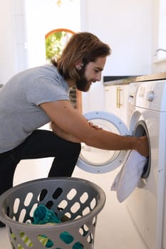 Caucasian man wearing gray tshirt and doing laundry. staying at home in isolation during quarantine lockdown.