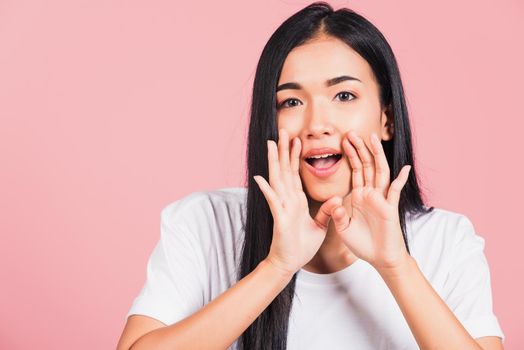 Asian happy portrait beautiful cute young woman teen standing hand on mouth talking whisper secret rumor studio shot isolated on pink background, Thai female looking to camera with copy space