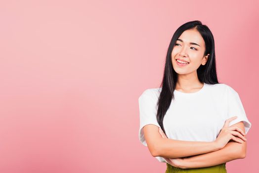 Asian happy portrait beautiful cute young woman standing her smile confidence with crossed arms isolated, studio shot on pink background and copy space, Thai female looking to side away