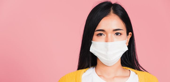 Closeup face Asian beautiful young woman wearing medical mask protection against germs for prevent infection coronavirus, COVID-19, studio shot isolated on pink background, medical health care concept