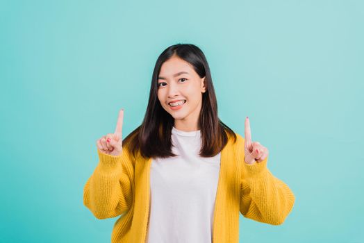 Portrait Asian beautiful young happy woman teen smiling show white teeth she's pointing finger up to empty space studio shot isolated on blue background, Dental health concept
