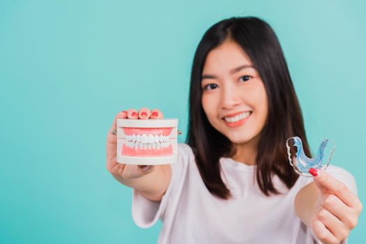 Portrait young Asian beautiful woman smiling holding silicone orthodontic retainers for teeth retaining tools after removable braces, Female hold model teeth before, Orthodontics dental healthy care