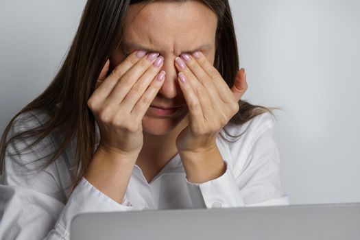 Tired woman suffering from eyes pain after working on the computer. Woman touching painful eyes. High quality photo