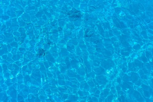 Background of water in blue swimming pool, water surface with sun reflection