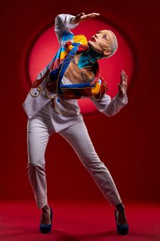 Studio shot of a stylish young woman posing against a red background.