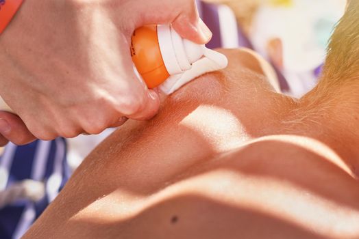 Woman apply protective sunscreen on boy's shoulders skin