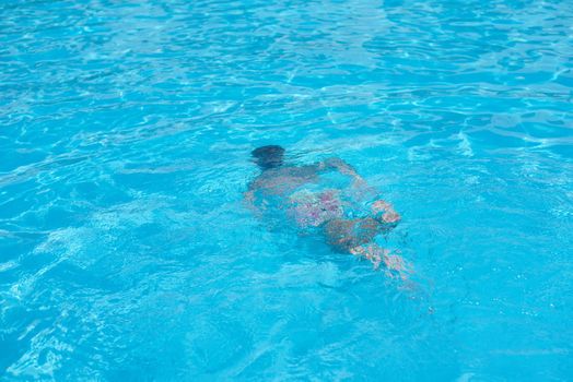 Boy in diving mask swim underwater in swimming pool