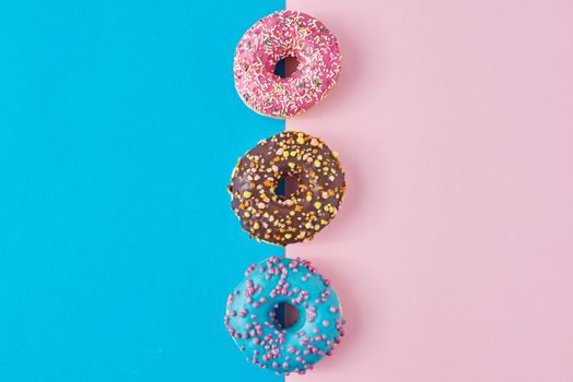 Donuts on pastel pink and blue background. Minimalism creative food composition. Flat lay style