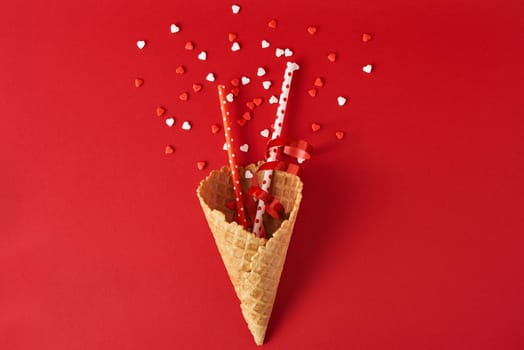 Festive ice cream cone with decorations and confetti on red backgrond, top view flat lay. Creative minimalism concept