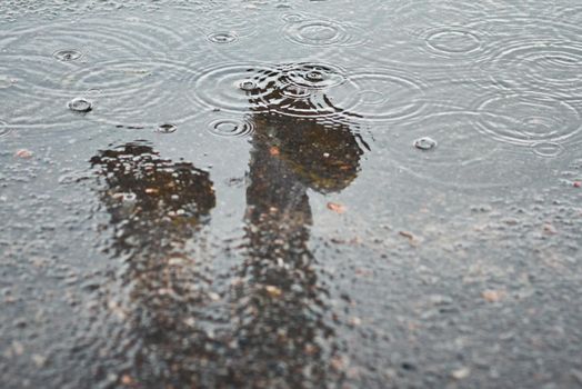 Reflection of two rainboots in puddle at rainy day