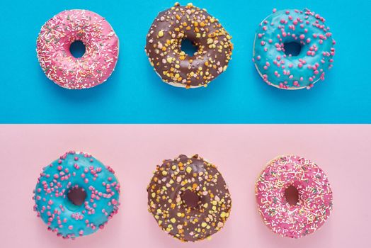 Donuts on pastel pink and blue background. Minimalism creative food composition. Flat lay style