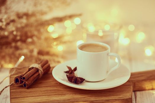 Cup of coffee with garland lights and decoration on table. Cozy home concept