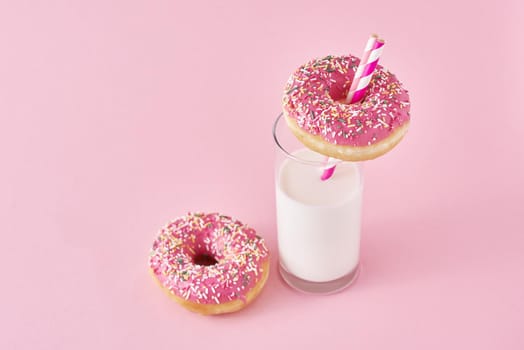 Donuts with glass of milk on pink background